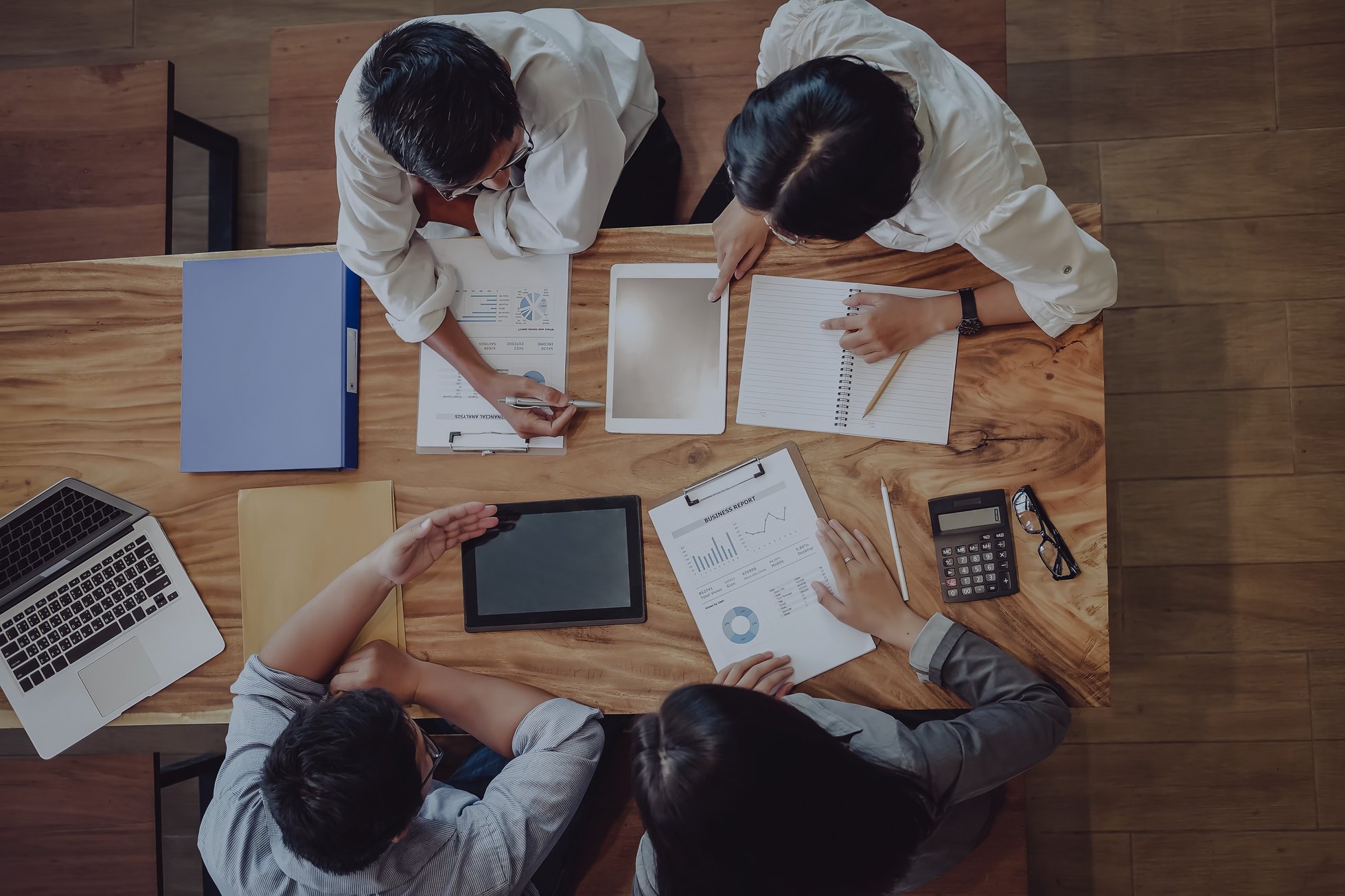 a group of people sitting around a table with papers and laptops